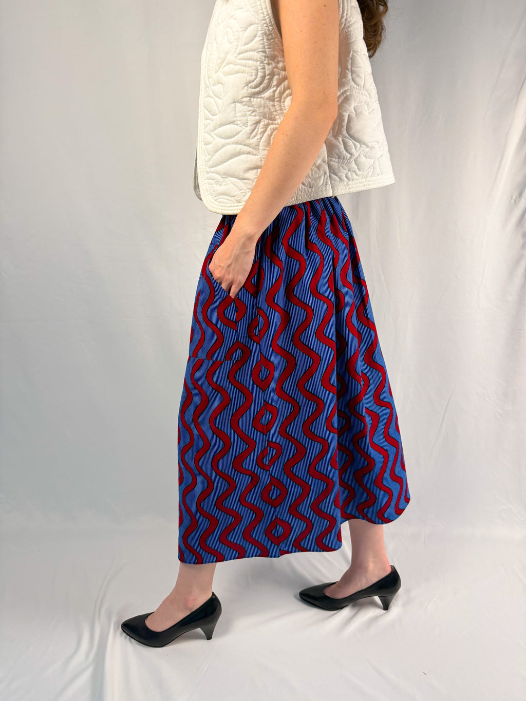 Person wearing a blue and red patterned skirt on a plain background onsem