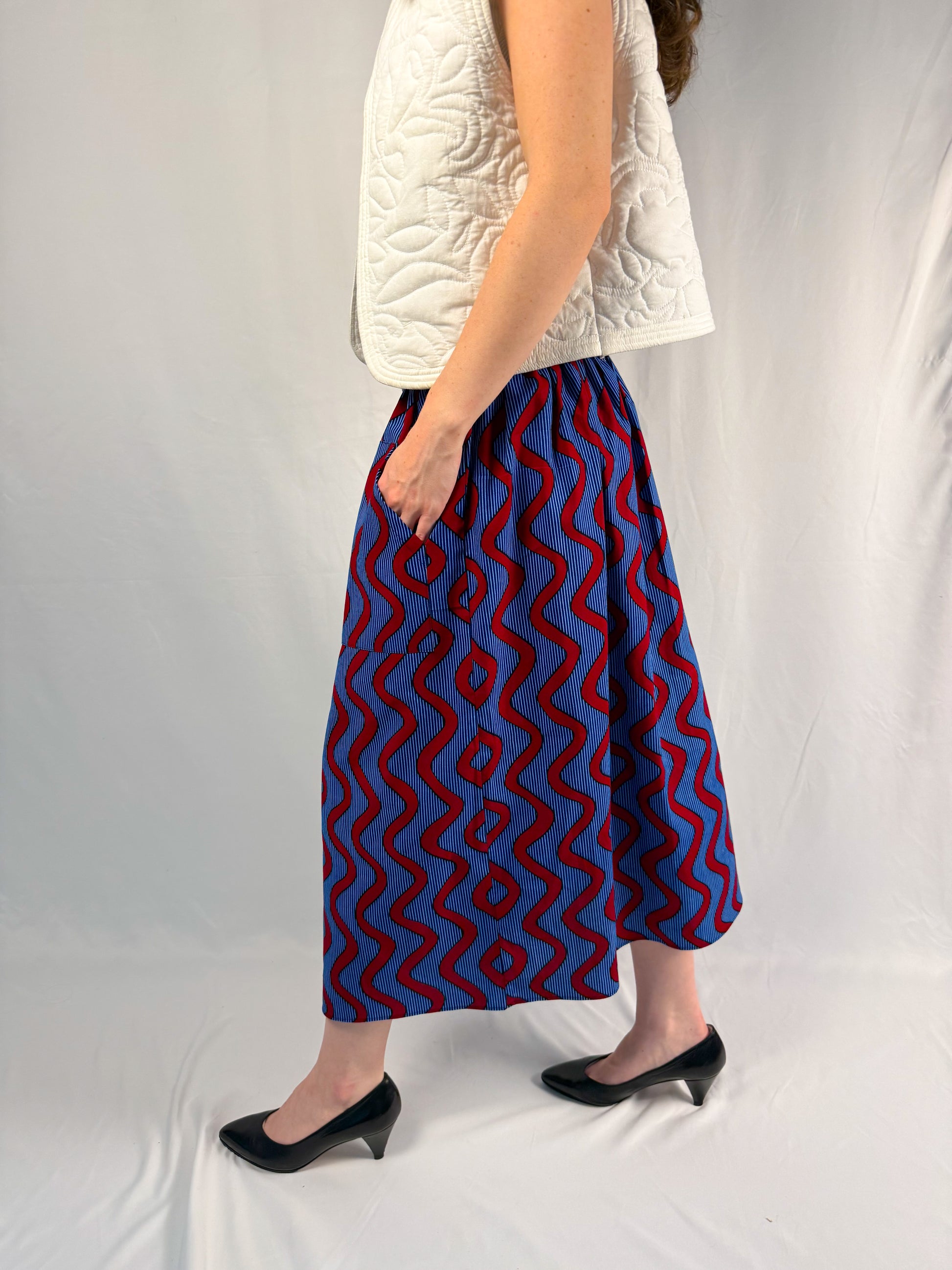 Person wearing a blue and red patterned skirt on a plain background