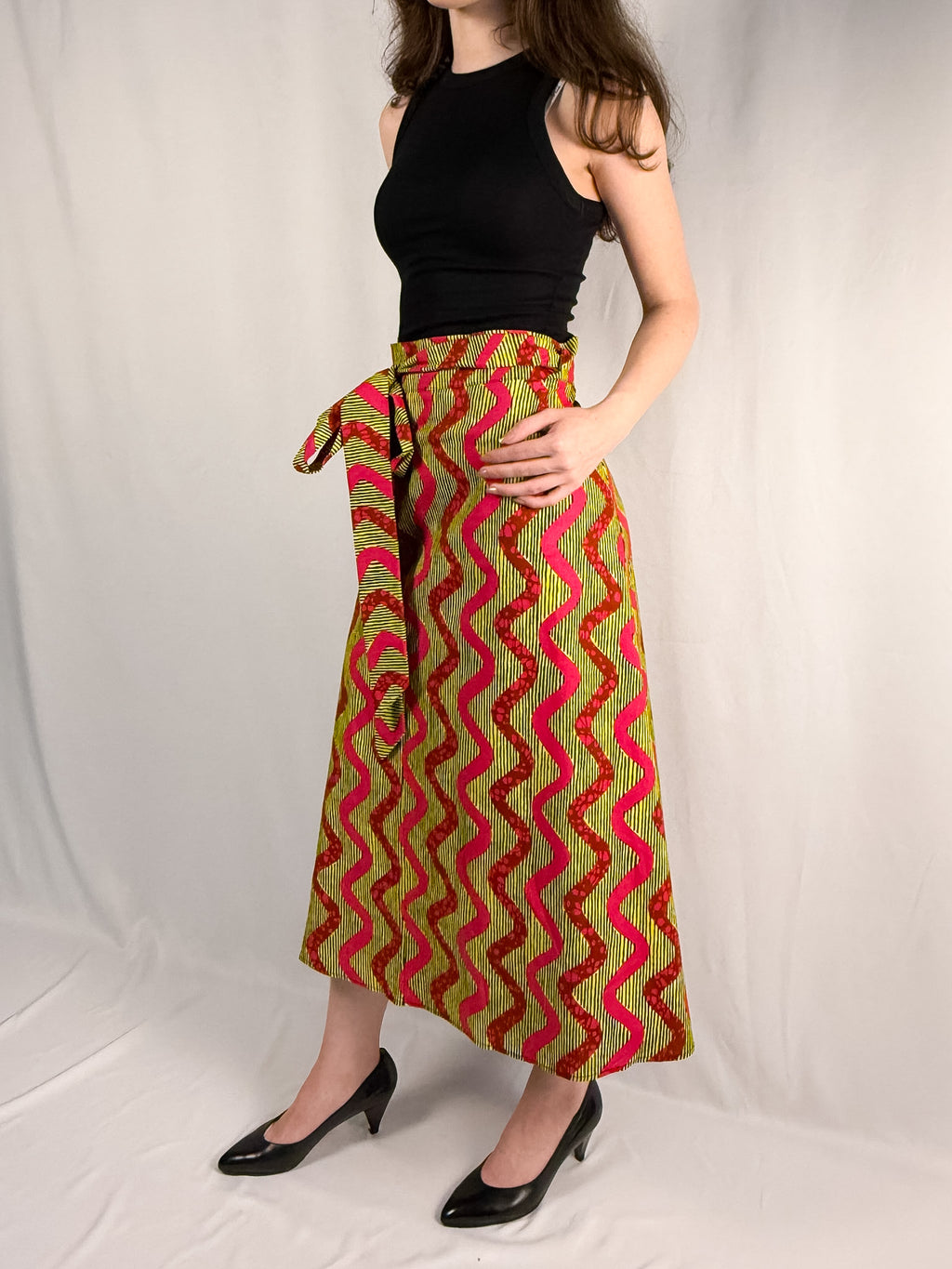 Person wearing a colorful patterned skirt on a white background onsem
