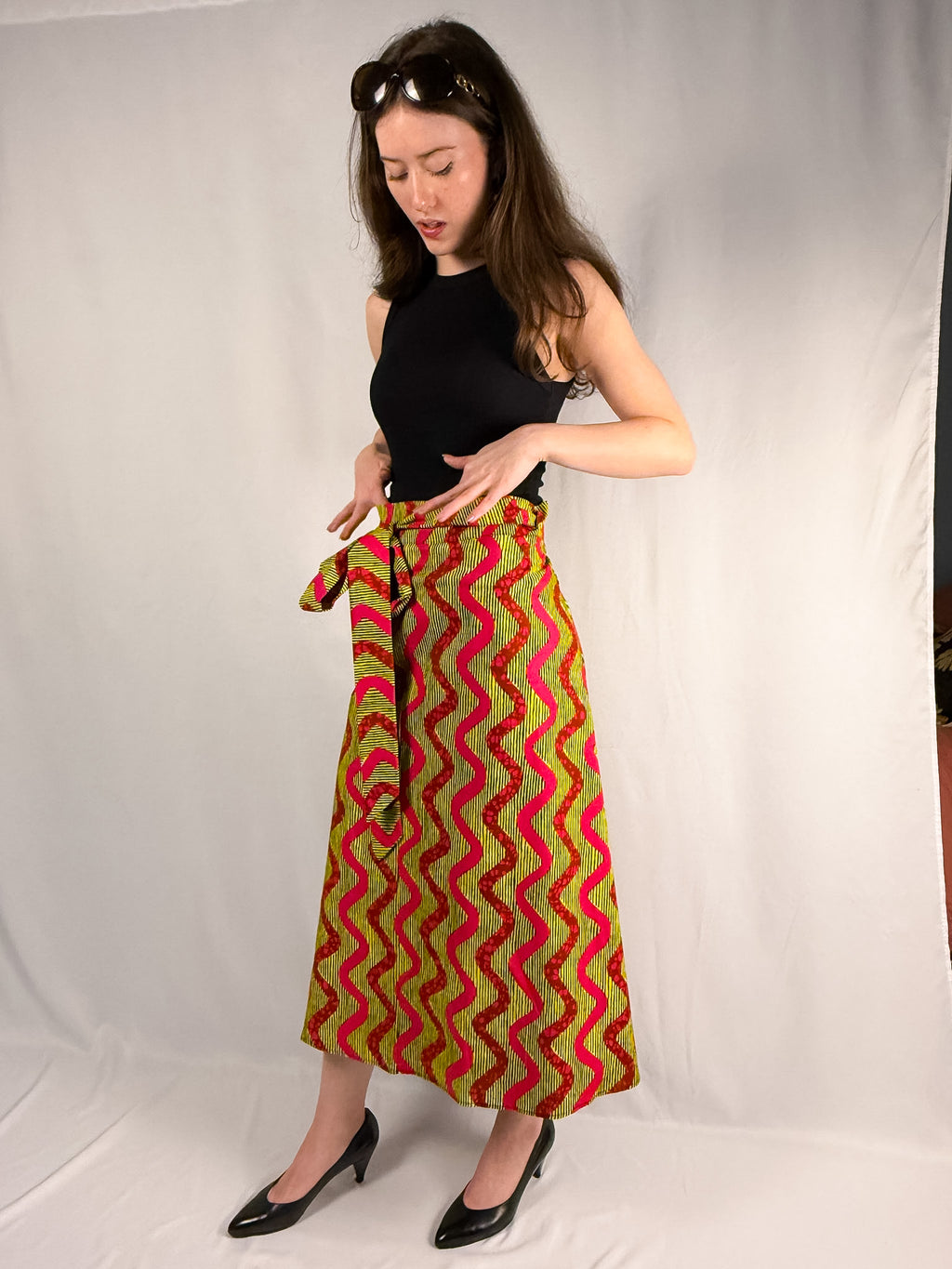 Woman wearing a colorful patterned skirt with a black top against a white background