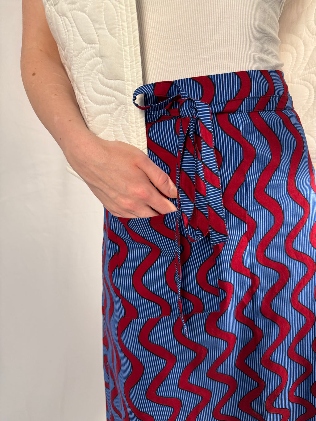 Person wearing a blue and red patterned skirt with a white top against a light background onsem