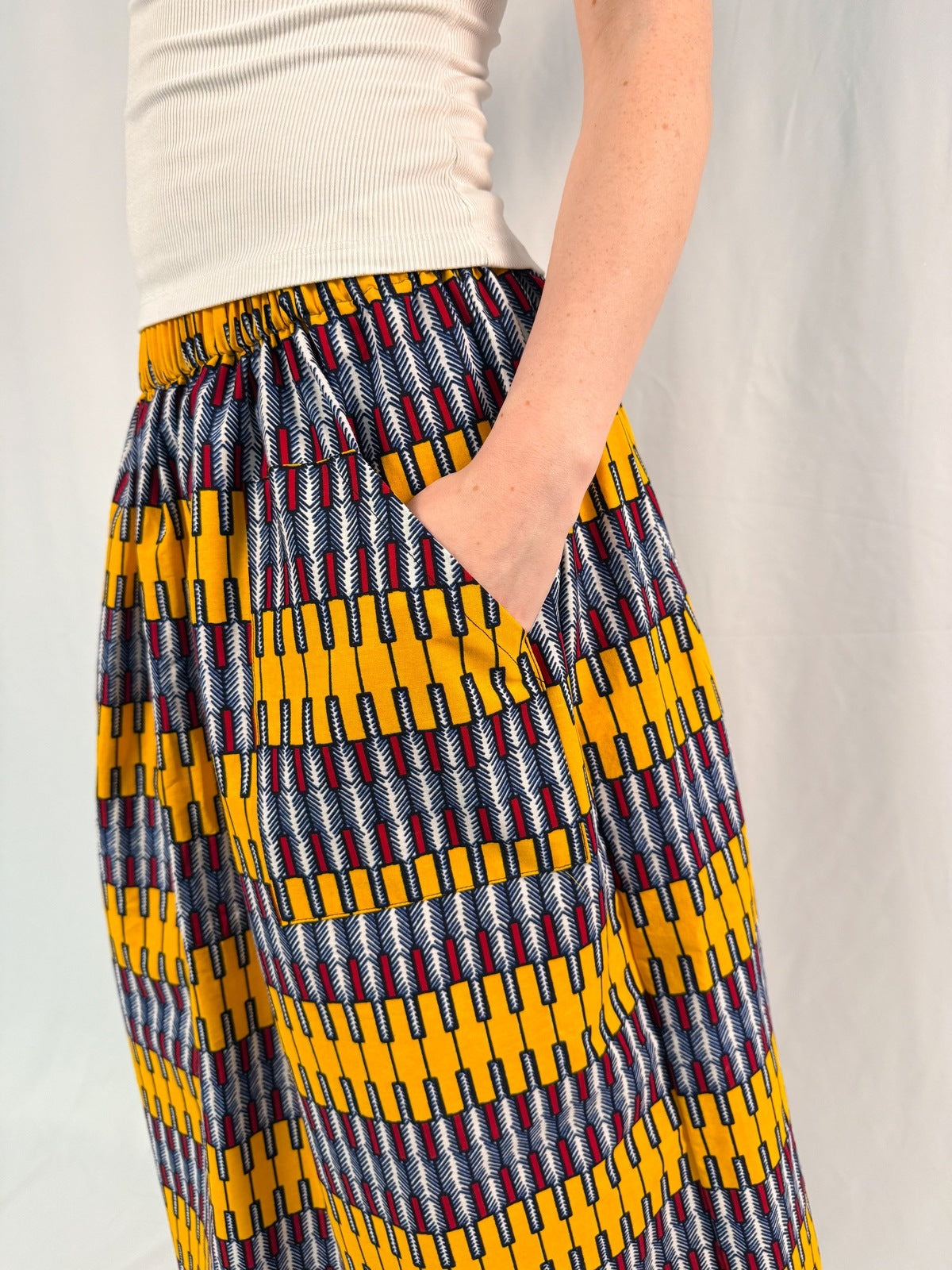 Person wearing a colorful patterned skirt with a plain background - onsem