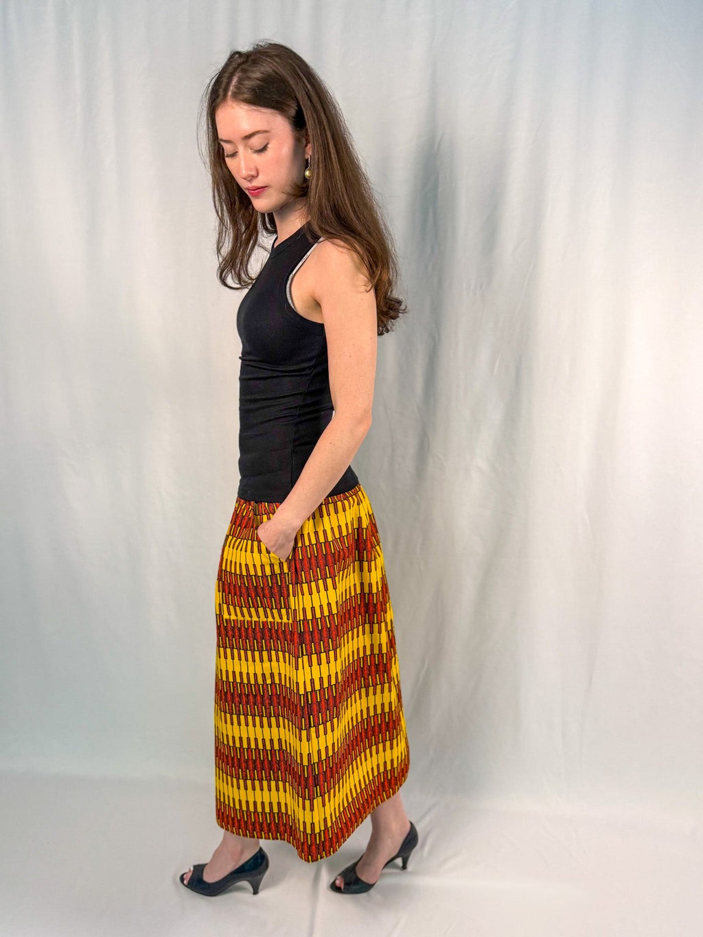 Woman wearing a black top and colorful skirt against a white background onsem