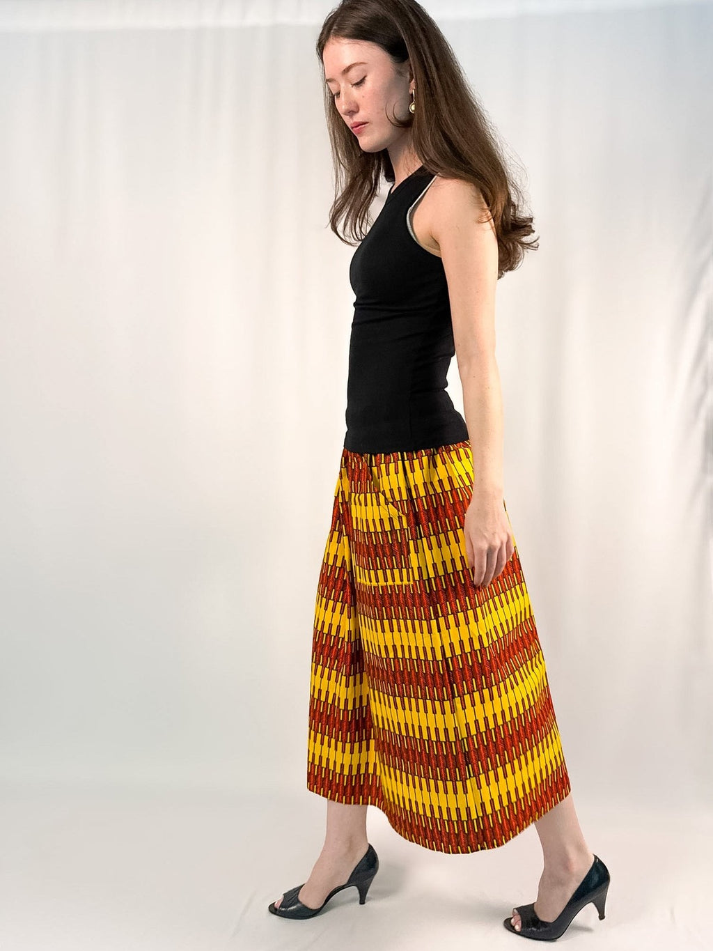 Woman wearing a black top and colorful patterned skirt on a white background onsem
